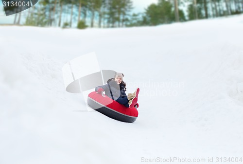 Image of happy teenage girl sliding down on snow tube