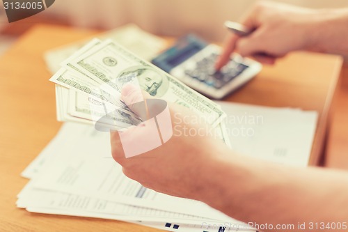 Image of close up of man counting money and making notes