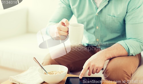 Image of close up of man with tablet pc having breakfast