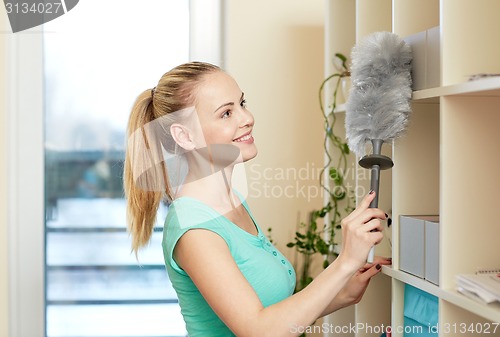 Image of happy woman with duster cleaning at home