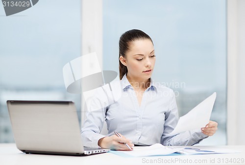 Image of businesswoman with laptop and charts in office