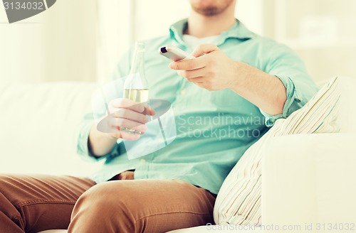 Image of man with beer and remote control at home