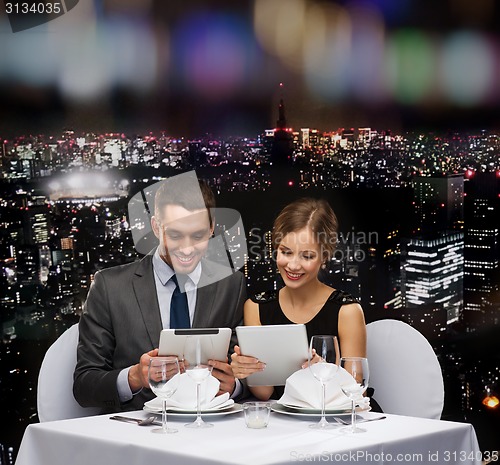 Image of couple with menus on tablet pc at restaurant