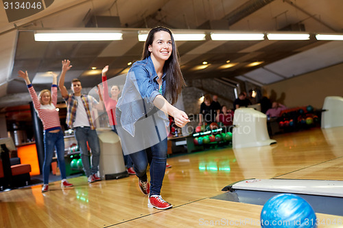 Image of happy young woman throwing ball in bowling club