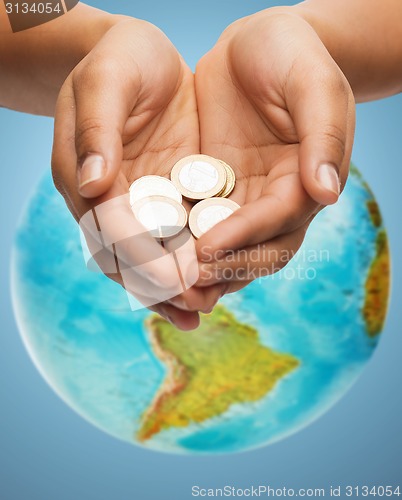 Image of cupped hands holding euro coins over earth globe