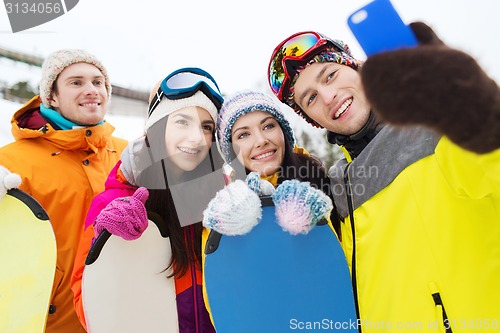 Image of happy friends with snowboards and smartphone