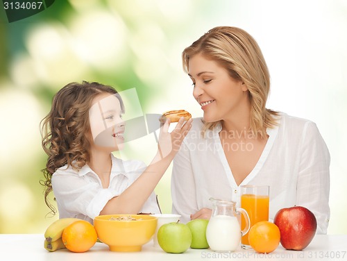Image of happy mother and daughter eating breakfast