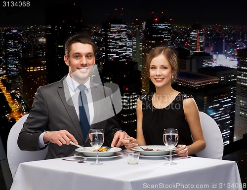 Image of smiling couple eating main course at restaurant