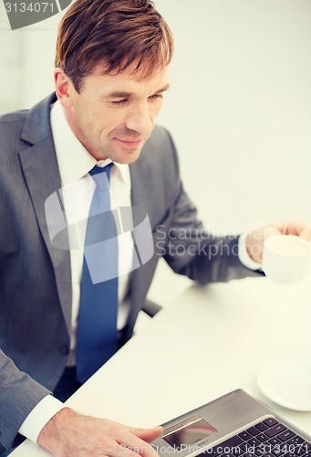 Image of smiling businessman working with laptop computer