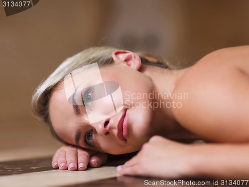 Image of young woman lying on hammam table in turkish bath