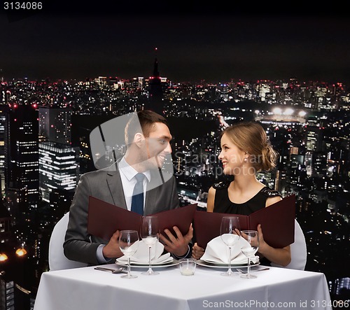 Image of smiling couple with menus at restaurant