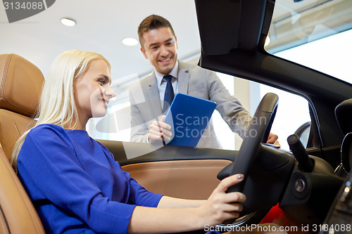 Image of happy woman with car dealer in auto show or salon