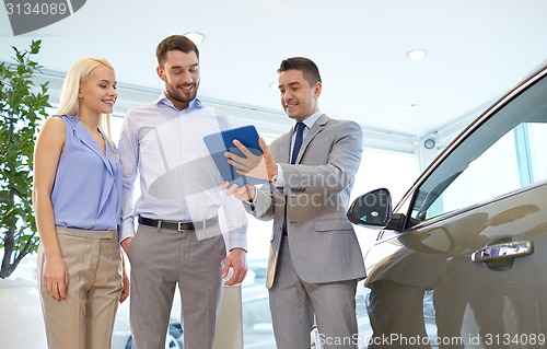 Image of happy couple with car dealer in auto show or salon