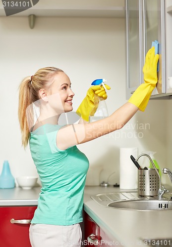 Image of happy woman cleaning cabinet at home kitchen