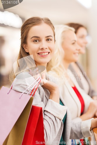 Image of happy young women with shopping bags in mall