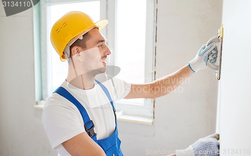 Image of smiling builder with grinding tool indoors