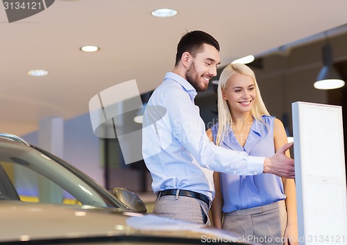 Image of happy couple buying car in auto show or salon