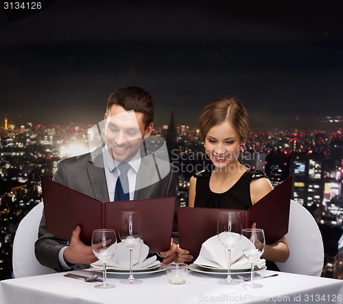 Image of smiling couple with menus at restaurant