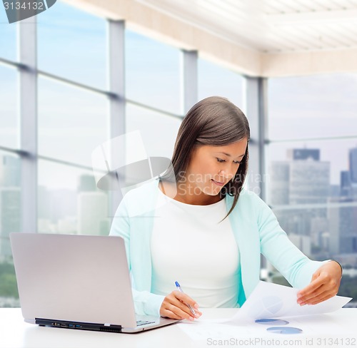 Image of smiling woman with laptop computer and papers