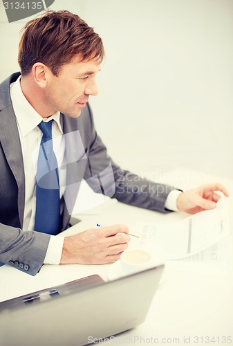 Image of businessman with laptop computer and documents