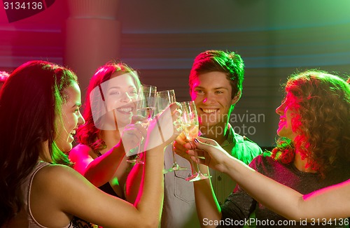 Image of smiling friends with glasses of champagne in club