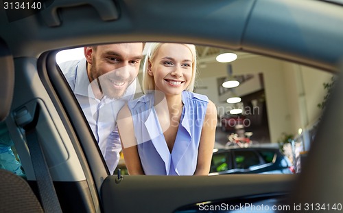 Image of happy couple buying car in auto show or salon