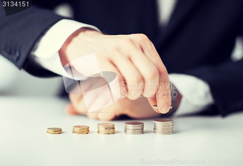 Image of man putting stack of coins into one row