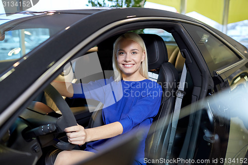 Image of happy woman inside car in auto show or salon