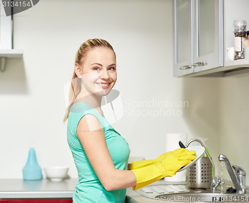 Image of happy woman washing dishes at home kitchen