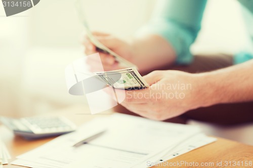 Image of close up of man counting money and making notes