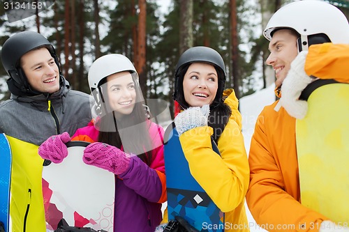 Image of happy friends in helmets with snowboards talking