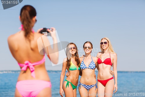 Image of group of smiling women photographing on beach