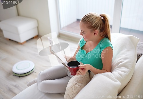 Image of happy woman reading magazine with tea cup at home