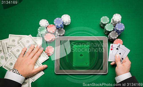 Image of casino poker player with cards, tablet and chips