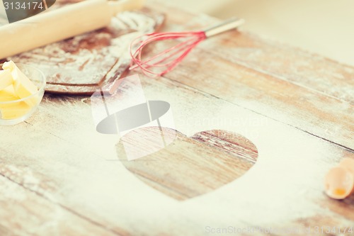 Image of close up of heart of flour on wooden table at home