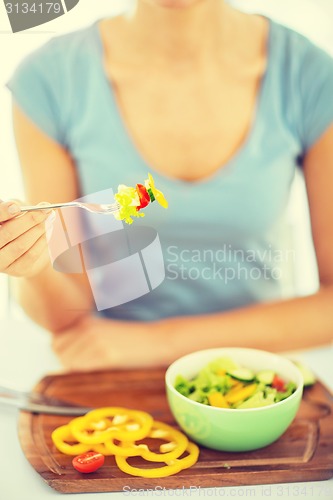 Image of woman hand holding fork with vegetables