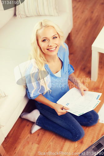 Image of smiling woman with papers, laptop and calculator