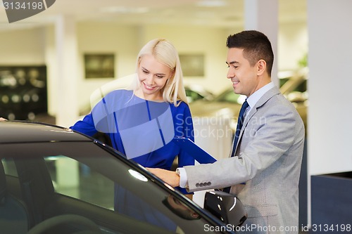 Image of happy woman with car dealer in auto show or salon