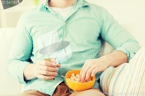 Image of close up of man with popcorn and beer at home