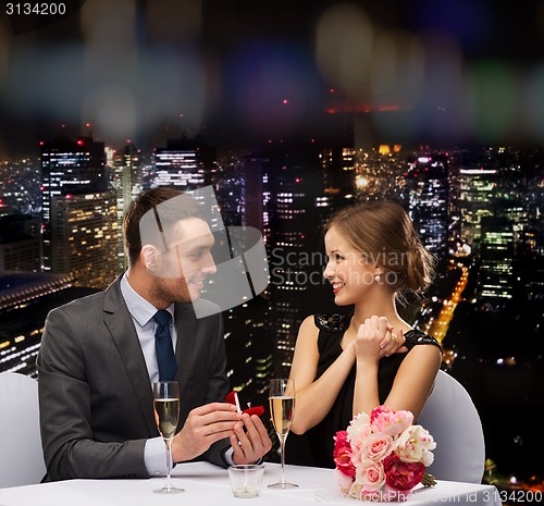 Image of man proposing to his girlfriend at restaurant