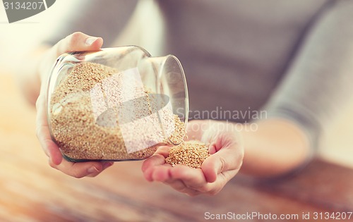 Image of close up of female emptying jar with quinoa