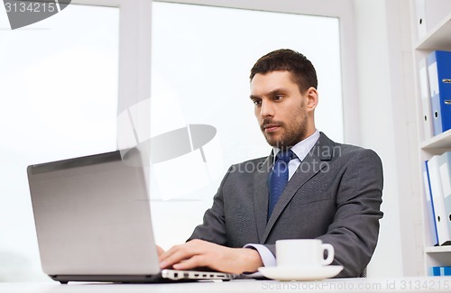 Image of businessman with laptop typing in office