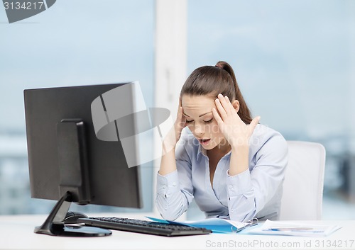 Image of stressed woman with computer and documents