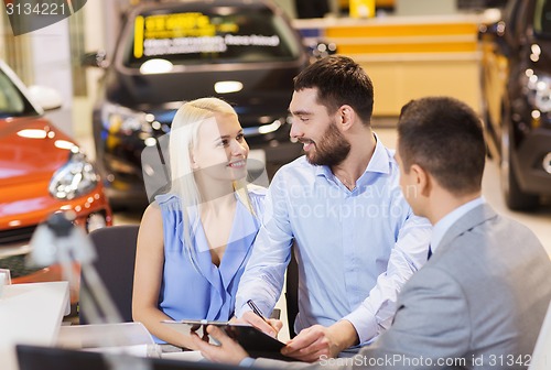 Image of happy couple with car dealer in auto show or salon