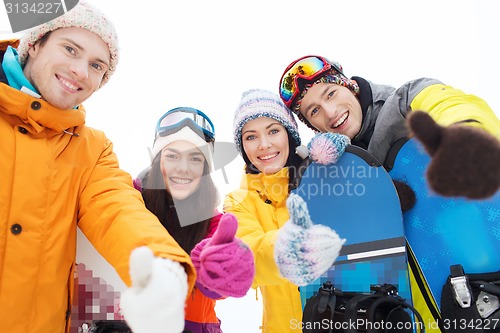 Image of happy friends with snowboards showing thumbs up