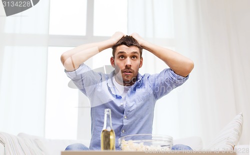 Image of smiling man watching sports at home