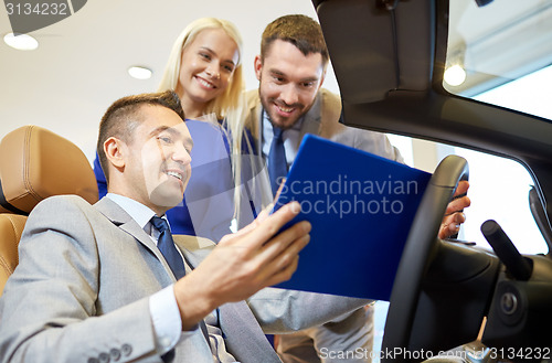 Image of happy couple with car dealer in auto show or salon