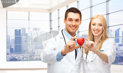 Image of happy young doctors cardiologists with red heart