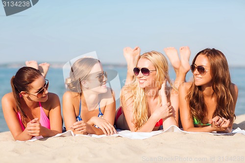 Image of group of smiling women in sunglasses on beach