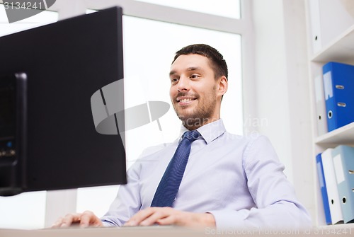 Image of smiling businessman with computer in office